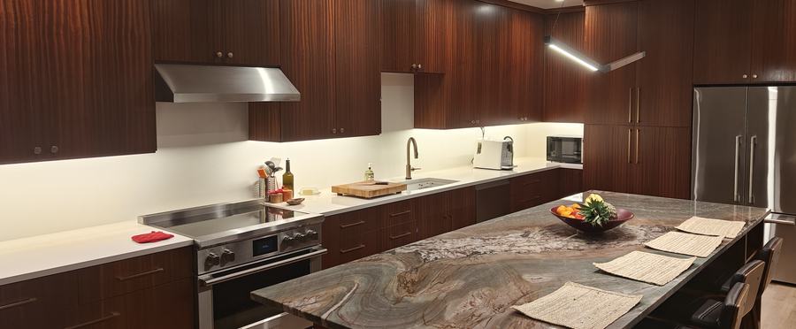 Wide view of the kitchen with dark wood cabinetry and a stone island